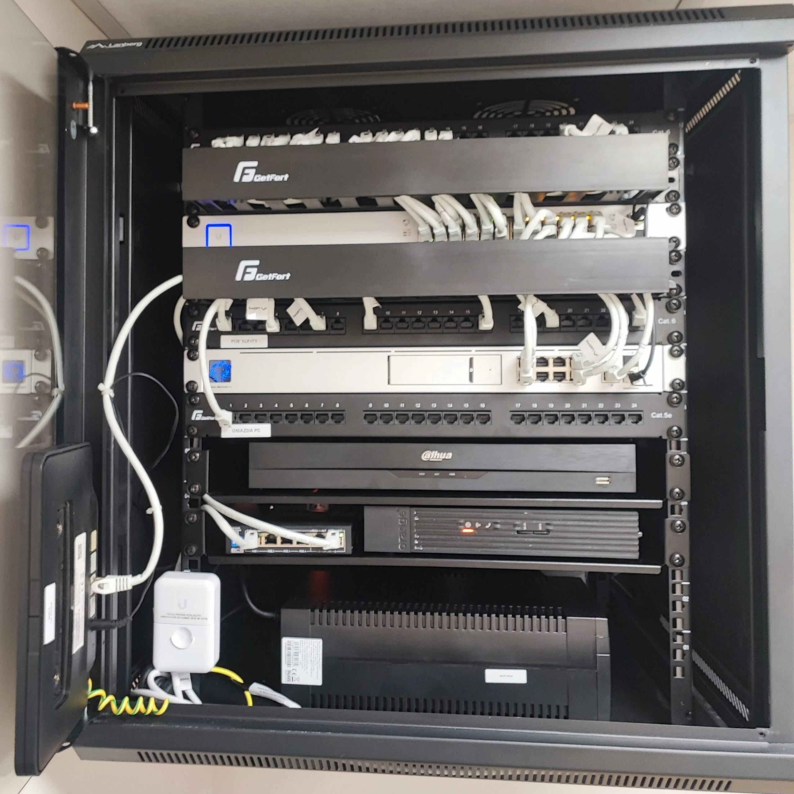 Szafa rackowa z profesjonalnie zainstalowanymi urządzeniami sieciowymi, w tym przełącznikami, routerami i systemami monitoringu, przedstawiająca zorganizowaną infrastrukturę IT.